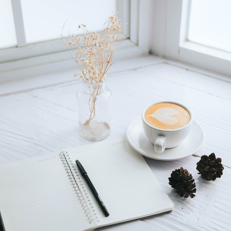Writing Your Story - Open book with blank pages a pen and a latte sitting on a table